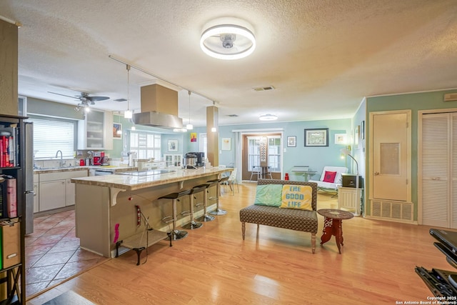 9518 Wahada, San Antonio, TX 78217 - kitchen with a kitchen breakfast bar, a textured ceiling, light countertops, light wood-style flooring, and a peninsula