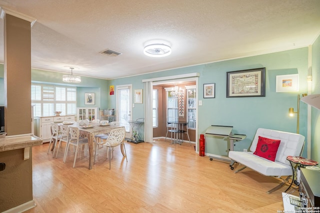 9518 Wahada, San Antonio, TX 78217 - dining room with light wood-style flooring, a chandelier, a textured ceiling, and crown molding