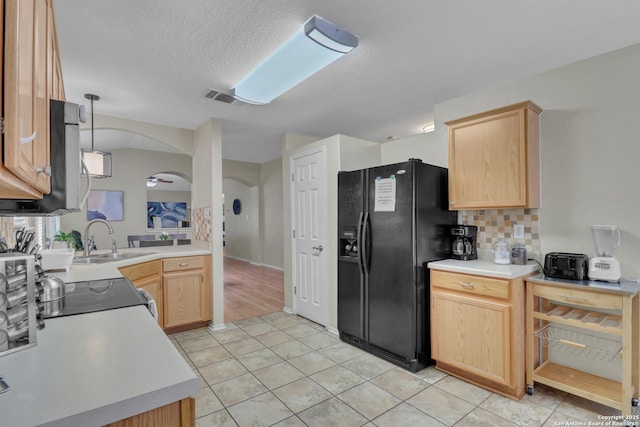 9427 Hacienda Acres, San Antonio, TX 78245 - kitchen featuring black refrigerator with ice dispenser, light brown cabinetry, arched walkways, light countertops, and decorative backsplash