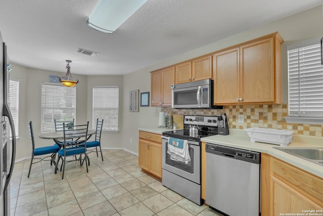 9427 Hacienda Acres, San Antonio, TX 78245 - kitchen featuring appliances with stainless steel finishes, tasteful backsplash, light countertops, and light brown cabinets