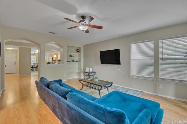 9427 Hacienda Acres, San Antonio, TX 78245 - living area featuring arched walkways, a ceiling fan, built in features, wood finished floors, and plenty of natural light