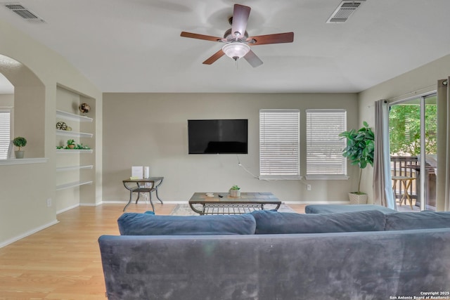 9427 Hacienda Acres, San Antonio, TX 78245 - living room featuring built in features, a ceiling fan, wood finished floors, and arched walkways