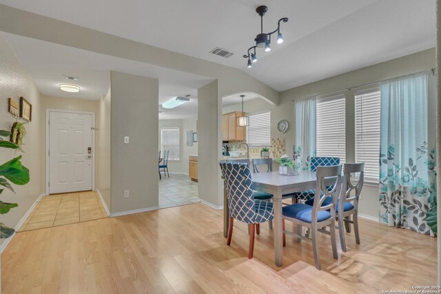 9427 Hacienda Acres, San Antonio, TX 78245 - dining space with light wood-style floors, vaulted ceiling, and arched walkways