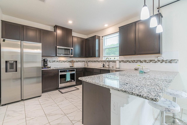 8298 Assumption Dr, San Antonio, TX 78254 - kitchen featuring appliances with stainless steel finishes, a peninsula, light marble finish floors, dark brown cabinetry, and light stone counters