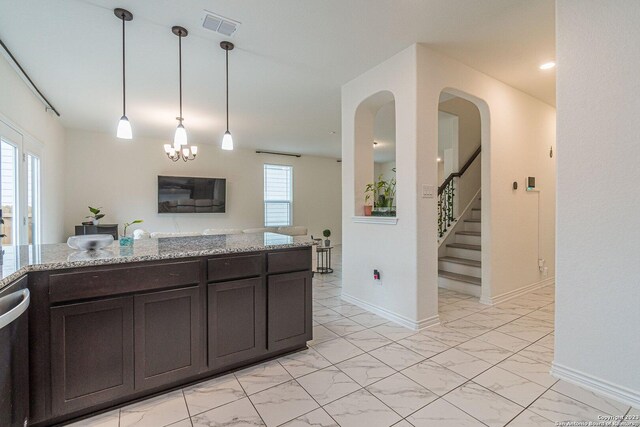 8298 Assumption Dr, San Antonio, TX 78254 - kitchen with light marble finish flooring, light stone counters, dark brown cabinets, and hanging light fixtures