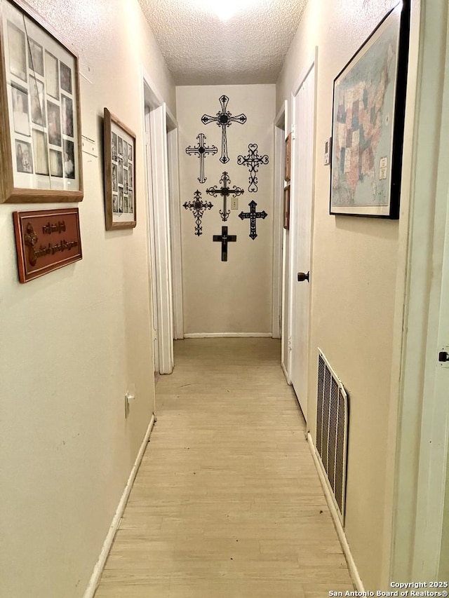 404 Alta, Pleasanton, TX 78064 - hallway featuring a textured ceiling and light wood-type flooring