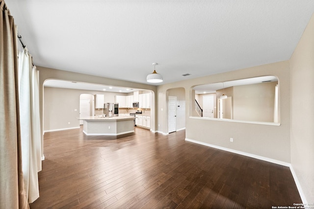 11406 Sawyer Vly, San Antonio, TX 78254 - unfurnished living room with arched walkways and dark wood-type flooring