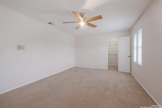 6403 Port Royal, San Antonio, TX 78244 - unfurnished bedroom featuring light carpet, a walk in closet, a ceiling fan, a closet, and a textured ceiling