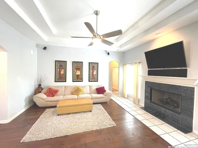 614 Slumber, San Antonio, TX 78260 - living area with arched walkways, a raised ceiling, a tiled fireplace, wood finished floors, and ceiling fan