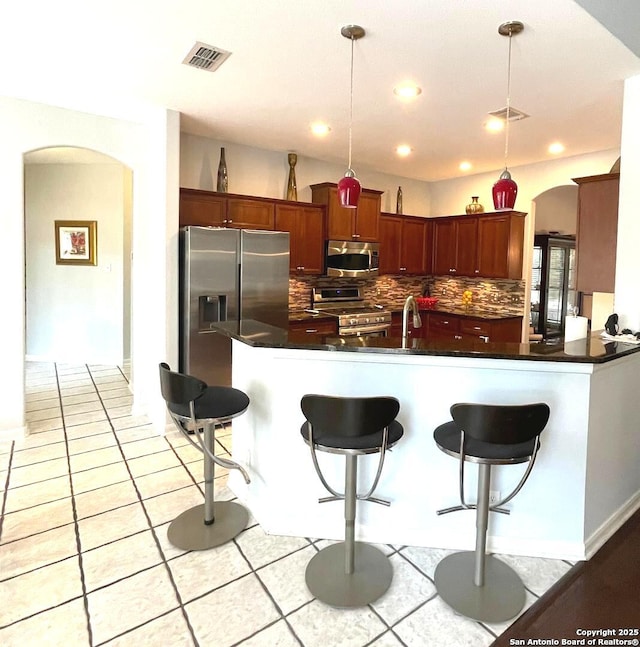 614 Slumber, San Antonio, TX 78260 - kitchen featuring arched walkways, stainless steel appliances, tasteful backsplash, dark countertops, and recessed lighting