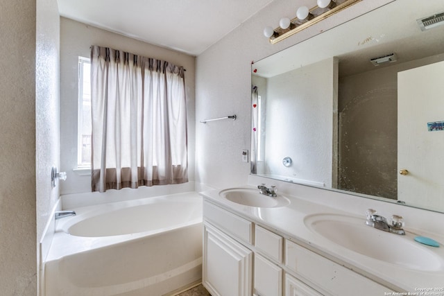 6051 Still Mdw, San Antonio, TX 78222 - bathroom featuring a bath, double vanity, and a textured wall