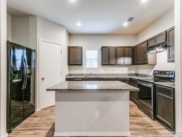 9410 Sandy Rdg, San Antonio, TX 78239 - kitchen featuring stainless steel electric range, black fridge with ice dispenser, under cabinet range hood, dark brown cabinets, and stone counters