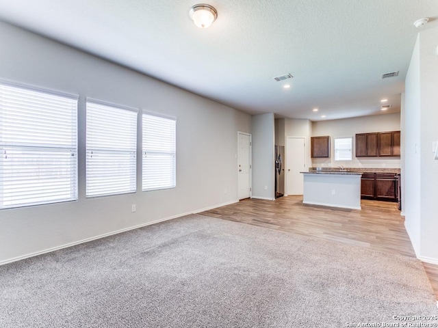 9410 Sandy Rdg, San Antonio, TX 78239 - unfurnished living room with light carpet, recessed lighting, and light wood-style flooring