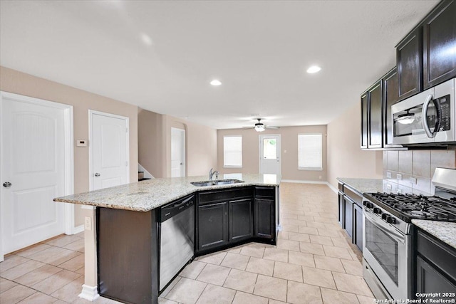 14055 Cremello Fls, San Antonio, TX 78254 - kitchen with appliances with stainless steel finishes, light tile patterned floors, a ceiling fan, a kitchen island with sink, and backsplash