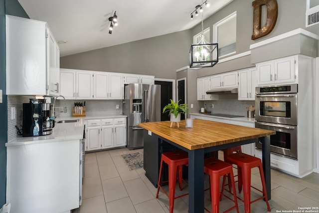 2102 Encino Clf, San Antonio, TX 78259 - kitchen featuring stainless steel appliances, butcher block countertops, high vaulted ceiling, tasteful backsplash, and white cabinetry
