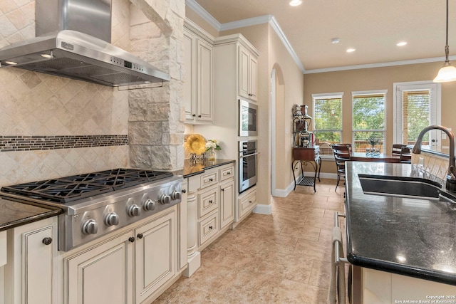 25926 Natal Plum, San Antonio, TX 78261 - kitchen with wall chimney range hood, appliances with stainless steel finishes, cream cabinets, decorative backsplash, and ornamental molding