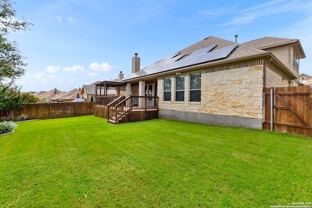 25926 Natal Plum, San Antonio, TX 78261 - rear view of house with stone siding, a fenced backyard, roof mounted solar panels, and a chimney