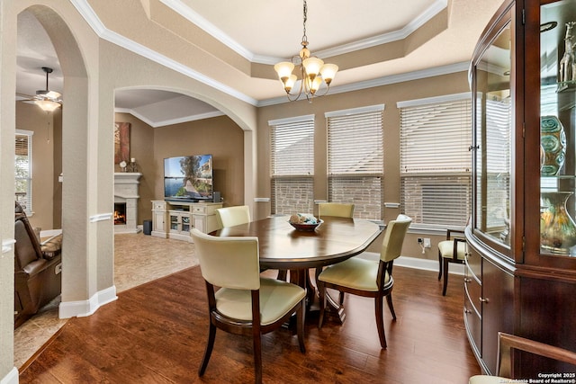 25926 Natal Plum, San Antonio, TX 78261 - dining area featuring a chandelier, dark wood finished floors, arched walkways, a warm lit fireplace, and crown molding