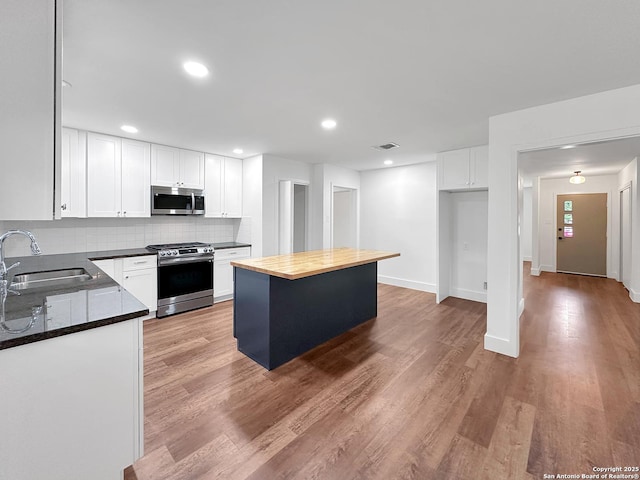 543 Cosgrove, San Antonio, TX 78210 - kitchen with stainless steel appliances, decorative backsplash, light wood-style flooring, white cabinetry, and recessed lighting