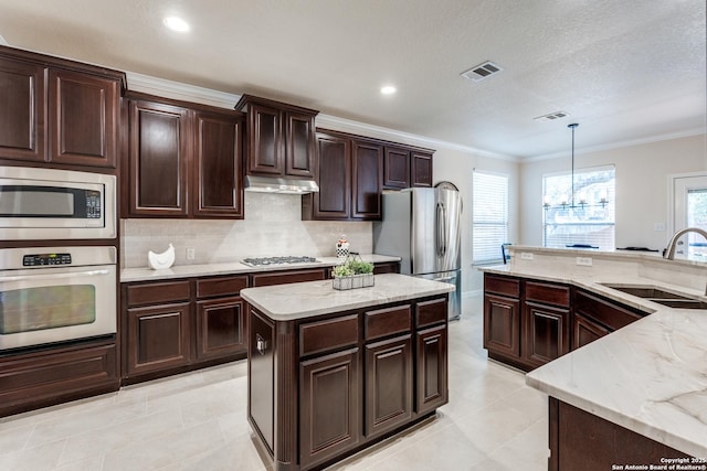3415 Crest Noche Dr, San Antonio, TX 78261 - kitchen with stainless steel appliances, a kitchen island, ornamental molding, decorative backsplash, and decorative light fixtures