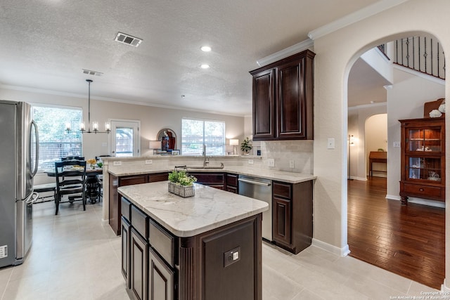 3415 Crest Noche Dr, San Antonio, TX 78261 - kitchen with stainless steel appliances, a peninsula, arched walkways, ornamental molding, and dark brown cabinetry