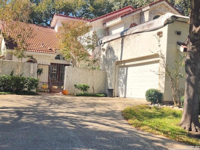 1022 River Gln W, San Antonio, TX 78216 - mediterranean / spanish-style home with driveway, stucco siding, a tile roof, an attached garage, and a gate