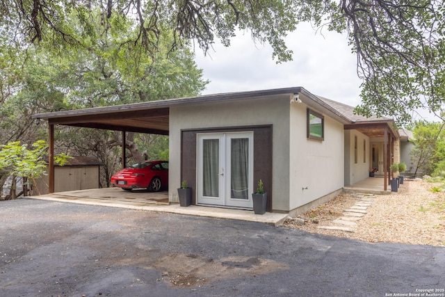 317 Saddle Mtn, Boerne, TX 78006 - view of property exterior featuring french doors, asphalt driveway, an attached carport, and an outbuilding