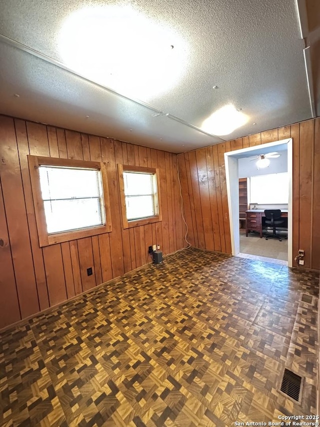 323 N Scenic Loop, Canyon Lake, TX 78133 - spare room featuring a textured ceiling, wooden walls, and an office area