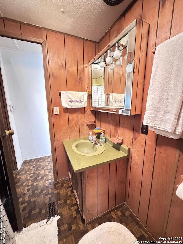 323 N Scenic Loop, Canyon Lake, TX 78133 - bathroom featuring vanity, a textured ceiling, and wood walls