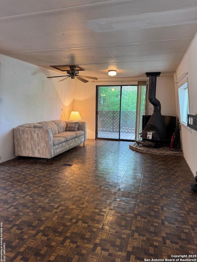 323 N Scenic Loop, Canyon Lake, TX 78133 - living area with a wood stove, a ceiling fan, and plenty of natural light