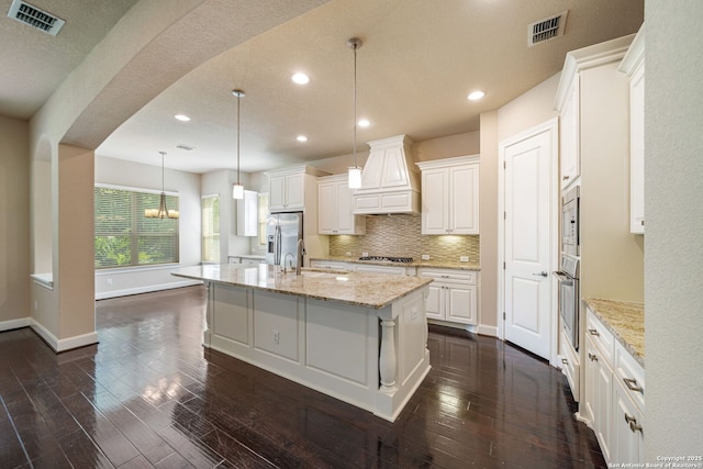 1702 Terra Alta, San Antonio, TX 78209 - kitchen featuring appliances with stainless steel finishes, premium range hood, a center island with sink, recessed lighting, and white cabinetry