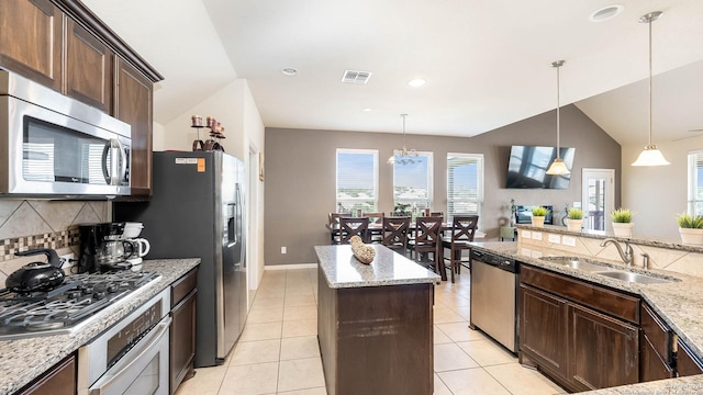 24514 Bliss Cyn, San Antonio, TX 78260 - kitchen with stainless steel appliances, decorative backsplash, dark brown cabinets, light stone countertops, and hanging light fixtures