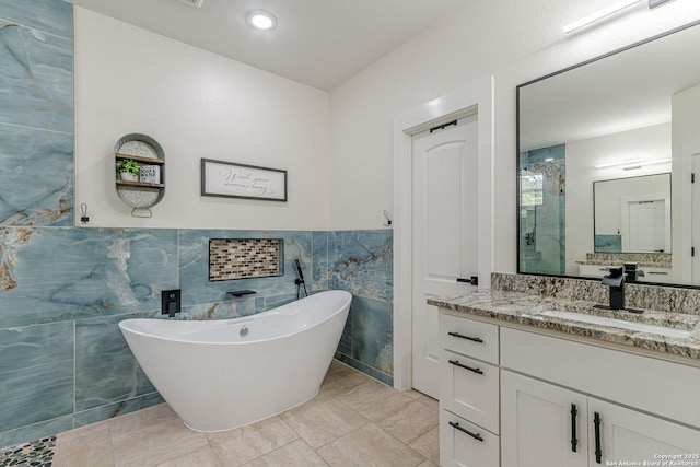 114 Mokukua Ln, Bastrop, TX 78602 - bathroom featuring tile walls, a soaking tub, vanity, a shower, and a wainscoted wall