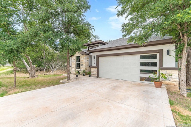 114 Mokukua Ln, Bastrop, TX 78602 - prairie-style home featuring stone siding, an attached garage, concrete driveway, and stucco siding