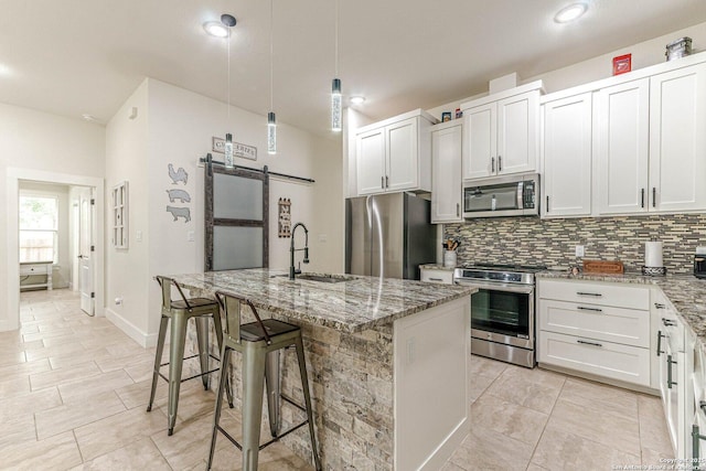 114 Mokukua Ln, Bastrop, TX 78602 - kitchen with stainless steel appliances, a barn door, backsplash, light stone countertops, and recessed lighting