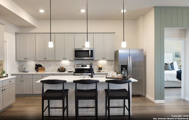 14426 Daphne Bnd, San Antonio, TX 78253 - kitchen featuring stainless steel appliances, dark wood-style flooring, backsplash, a kitchen breakfast bar, and a kitchen island with sink