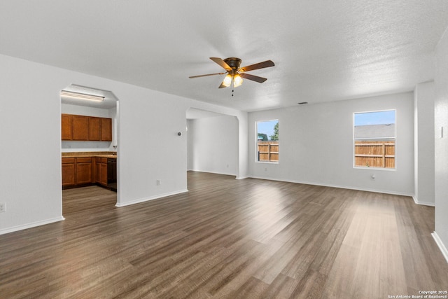 221 Passerina Spur, Schertz, TX 78154 - unfurnished living room featuring ceiling fan, arched walkways, and dark wood-type flooring