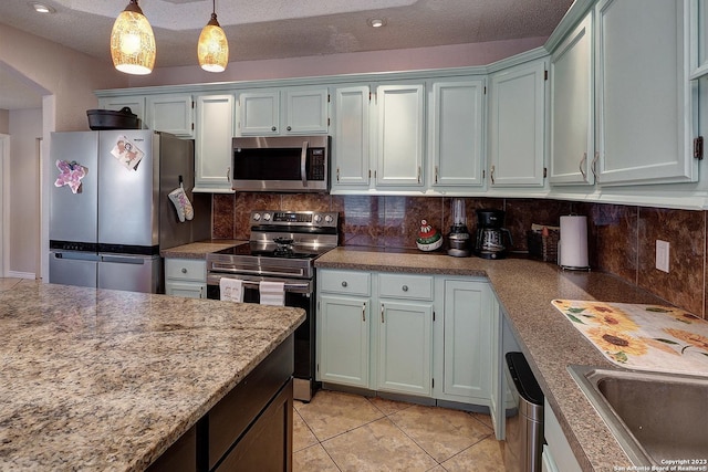 402 Hermine Blvd, San Antonio, TX 78212 - kitchen featuring appliances with stainless steel finishes, backsplash, light tile patterned floors, and decorative light fixtures