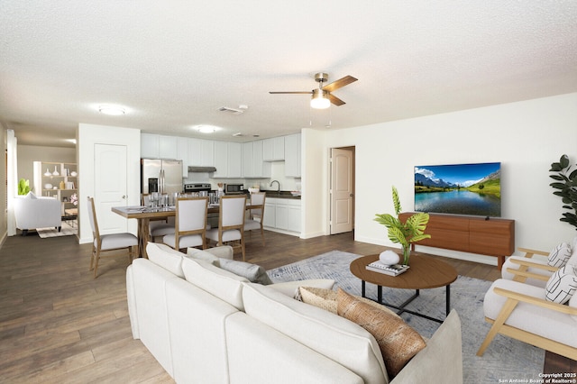 13139 Regency Bnd, San Antonio, TX 78249 - living area featuring dark wood-style floors, ceiling fan, and a textured ceiling