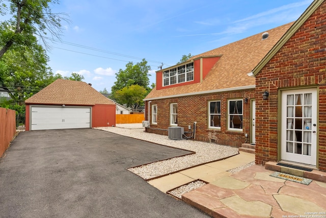 138 E Lullwood Ave, San Antonio, TX 78212 - view of side of property featuring a detached garage, roof with shingles, an outdoor structure, and brick siding