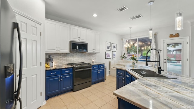 1739 Oak Gln, New Braunfels, TX 78132 - kitchen featuring appliances with stainless steel finishes, blue cabinetry, white cabinets, light tile patterned floors, and decorative backsplash