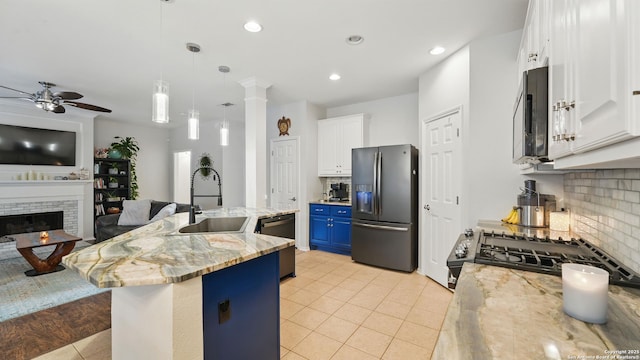1739 Oak Gln, New Braunfels, TX 78132 - kitchen featuring stainless steel appliances, blue cabinets, light tile patterned floors, a ceiling fan, and tasteful backsplash
