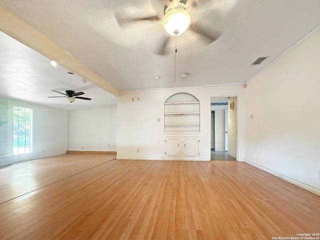 3923 Maxine, San Antonio, TX 78228 - unfurnished living room featuring ceiling fan, a textured ceiling, light wood-style flooring, and built in shelves