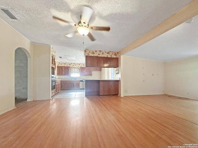 3923 Maxine, San Antonio, TX 78228 - unfurnished living room with arched walkways, light wood-type flooring, a textured ceiling, and ceiling fan