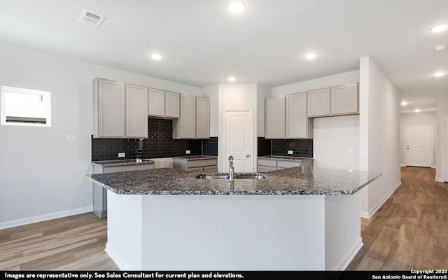11619 Cowper Horn, San Antonio, TX 78245 - kitchen featuring light wood-style floors, dark stone countertops, an island with sink, tasteful backsplash, and recessed lighting
