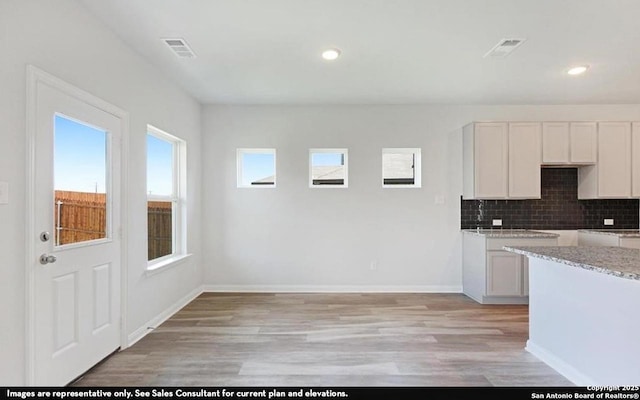 11619 Cowper Horn, San Antonio, TX 78245 - kitchen featuring light wood-type flooring, decorative backsplash, recessed lighting, white cabinetry, and light stone countertops