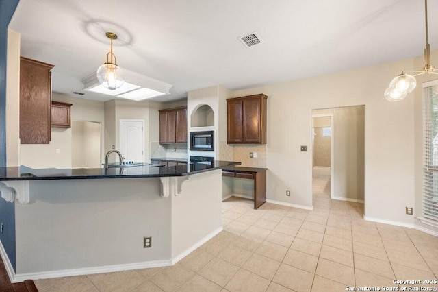 24831 Cloudy Crk, San Antonio, TX 78255 - kitchen featuring black microwave, a kitchen bar, backsplash, and hanging light fixtures