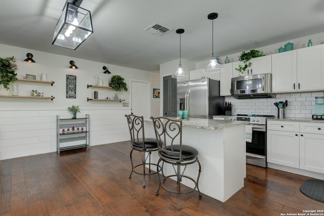 8211 Littleport, San Antonio, TX 78239 - kitchen with appliances with stainless steel finishes, open shelves, a breakfast bar area, a kitchen island, and white cabinets