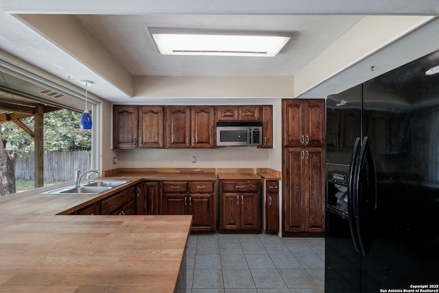 6914 Glen Gate, San Antonio, TX 78239 - kitchen featuring black refrigerator with ice dispenser, stainless steel microwave, wood counters, and light tile patterned flooring