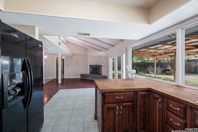 6914 Glen Gate, San Antonio, TX 78239 - kitchen with black refrigerator with ice dispenser, wooden counters, a fireplace with raised hearth, tile patterned floors, and open floor plan